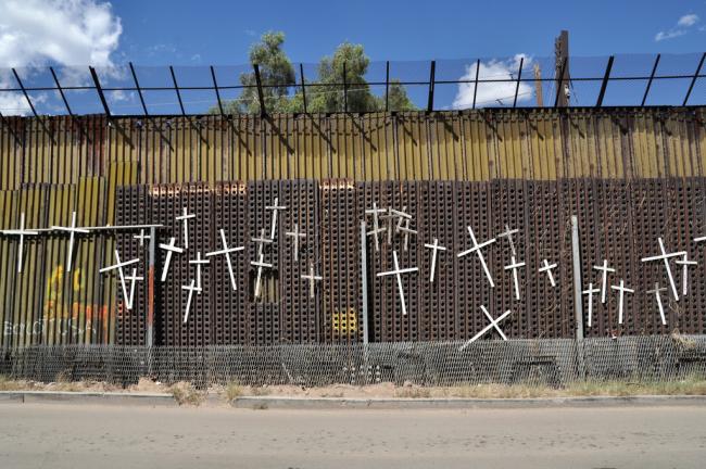 Crosses on the U.S.-Mexico border wall in Nogales, Sonora, commemorate migrants who have died while trying to cross into the United States (Jonathan McIntosh/Flickr)