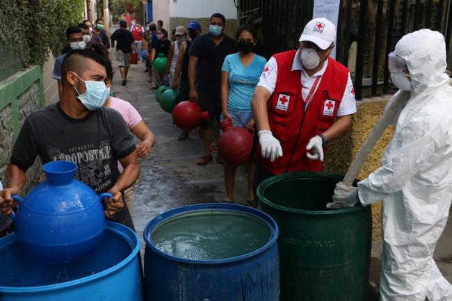 Vecinos de una zona de San Salvador recogen agua distribuida por la Cruz Roja Salvadoreña en marzo de 2020. (Cruz Roja Salvadoreña / Facebook) 