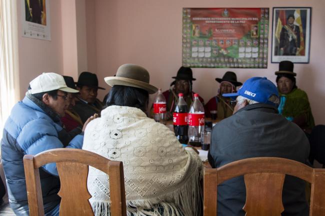 Bertha Quispe (center) meets local authorities in the town hall to discuss irrigation projects. They wear red ponchos, a sign of authority for the Aymara. (Photo by Irene Escudero)