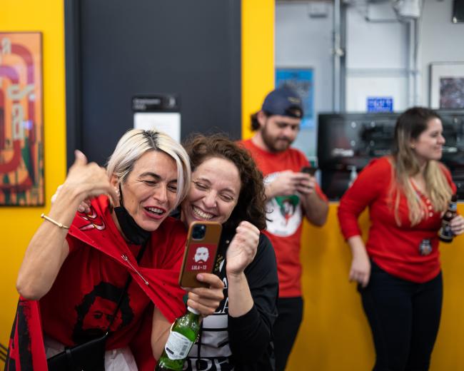 Defend Democracy in Brazil (DDB) volunteers Alessandra Luiza and Natalia de Campos celebrate Lula's victory via video call with a fellow DDB member who is in Brazil. (Guilherme Henrique)