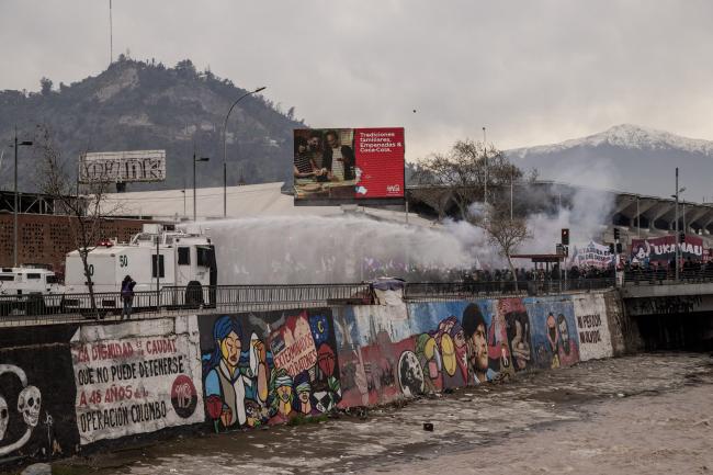 A police vehicle pummels demonstrators with water as they cross the Mapocho river on September 10, 2023. (Anita Pouchard Serra)