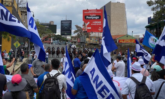 La Asociación Nacional de Empleados Públicos y Privados (ANEP) se enfrenta a una línea de policías a caballo durante las protestas en San José, Costa Rica, 1 de mayo de 2023. (Isabel Villalon)