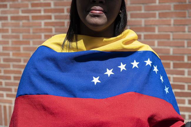 Una mujer cubierta con una bandera venezolana espera a la líder opositora María Corina Machado cerca de un colegio electoral en Los Chorros, al este de Caracas, el 28 de julio de 2024. (Marcelo Pérez del Carpio)