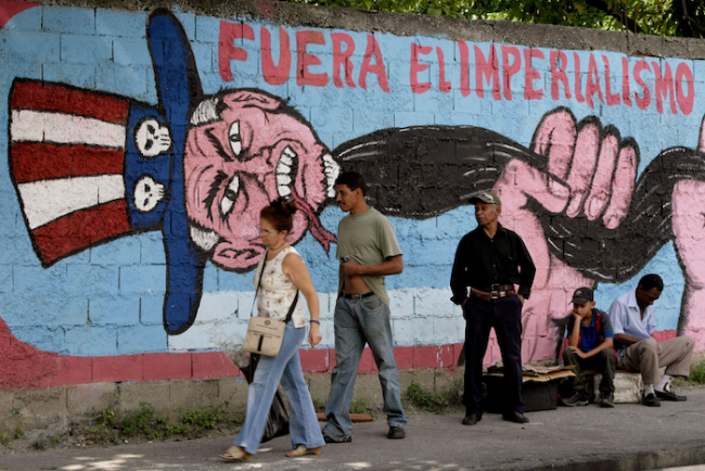 People pass in front of a mural reading 