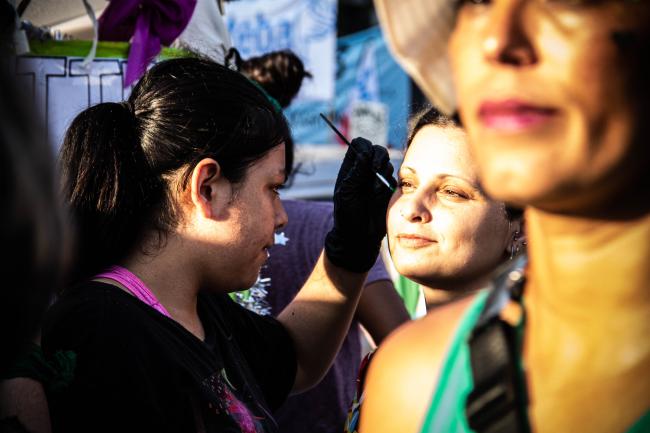 A protester adorns her friend's face with glitter (Virginia Tognola)