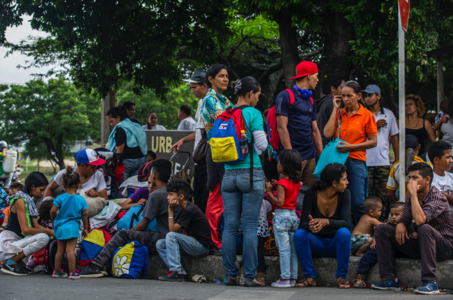 After leaving Venezuela, families sit on the sidewalk in front of a Red Cross help center in C?cuta, Colombia, April 3, 2019. Some travel with a tricolored backpack. (UNHCR / Vincent Tremeau)