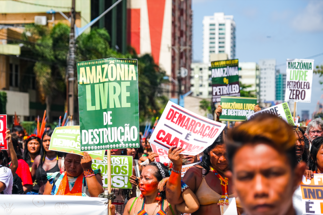 People march in Belém, Brazil, in defense of the Amazon, August 8, 2023. Messages on signs include 