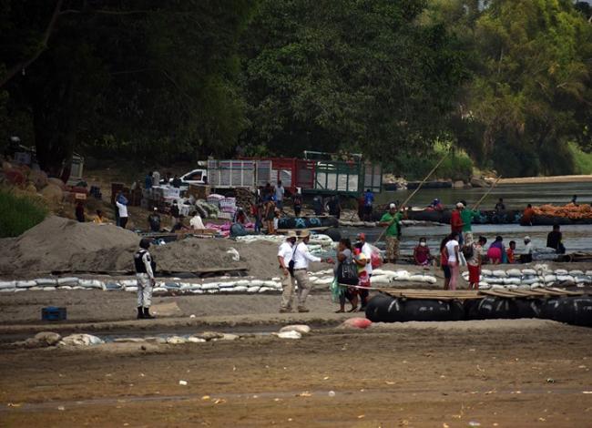 A National Guard member (left) and immmigration agents (center) on the banks of the Suchiate River in Chiapas, Mexico, while deployed in response to a migrant caravan. (Jorge Choy-Gómez)